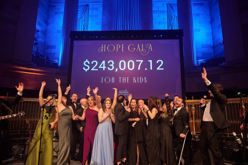 Hope Gala crowd celebrating with a screen behind them displaying funds raised, courtesy