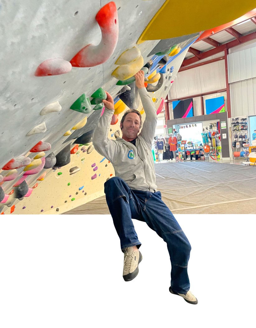 Seth Blumsack hanging off of a rock climbing wall, courtesy