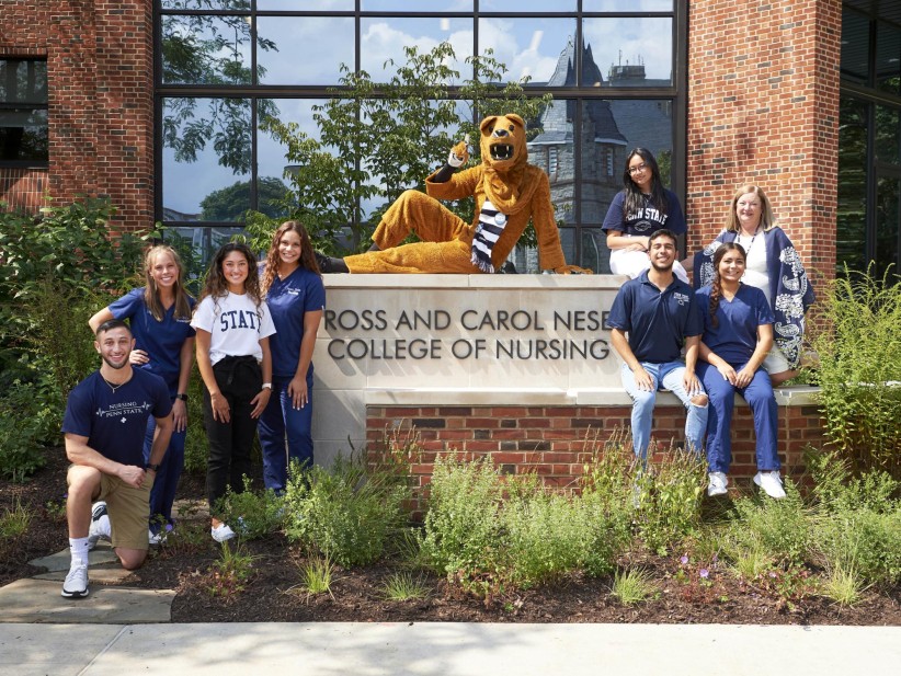 photo of students and Nittany Lion posing in front of the Ross and Carol Nese College of Nursing sign