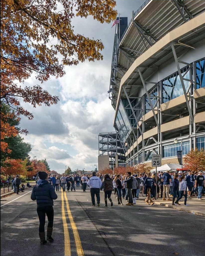photo of Nittany Lion fans walking down the road outside Beaver Stadium under cloudy skies amid fall leaves, by Nick Sloff '92 A&A