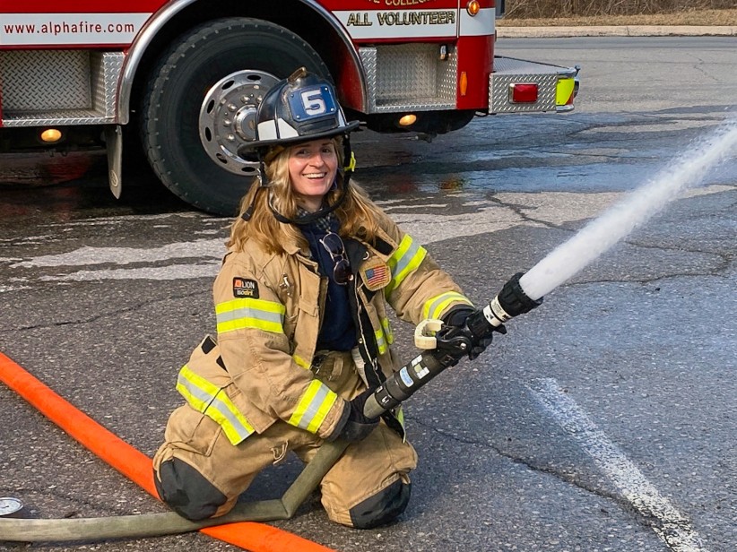 photo of Kollat in firefighter gear wielding a fire hose, courtesy