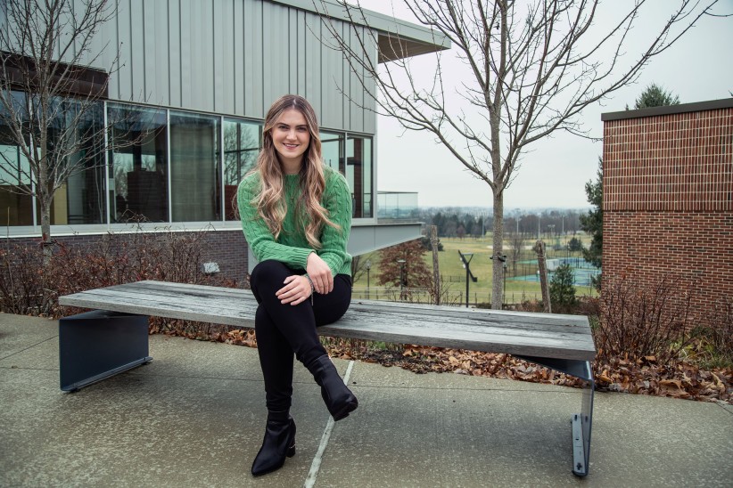 Avery Volz seated on a bench outside a Penn State York building, photo by Cardoni