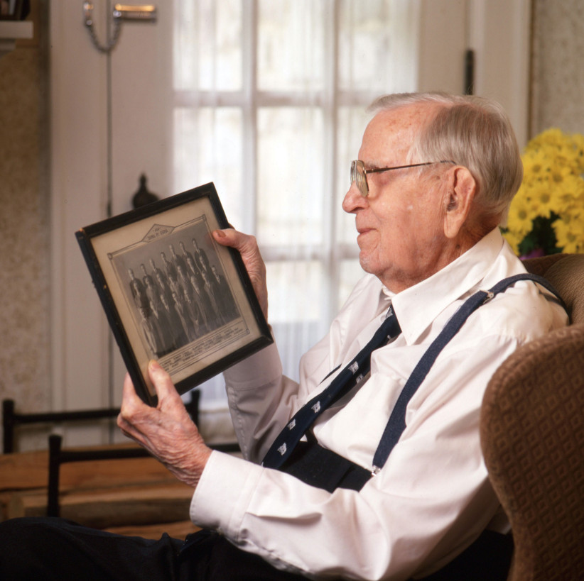 photo of White looking at a framed photo of former Penn State colleagues by Steve Tressler
