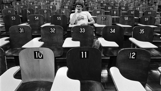 black and white photo of Pat Little in lecture hall in the 70s with numbered wooden seats, photo by Pat Little