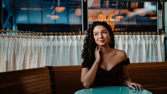 Lisa Rogali seated at a round green table in a cafe, photo by Jiyang Chen