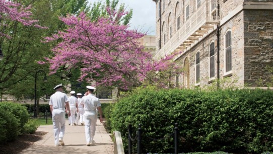 men in Navy uniforms walking on campus in spring time photo by Corinne Furjanic