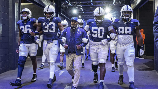 group photo of Smith and players walking onto the field out of a blue tunnel, photo by Mark Selders