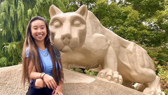 photo of Yu sitting with the Lion Shrine, courtesy