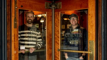 Corner Room owners standing behind iconic glass of revolving doors