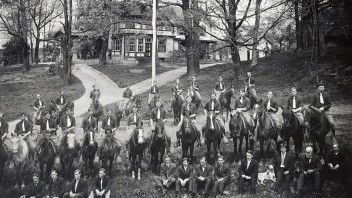 Black and white image of students and horses on a lawn