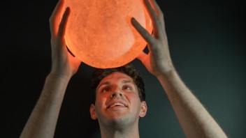 Nolan Roth examines a glowing model of a planetary body, photo by Cardoni