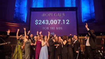 Hope Gala crowd celebrating with a screen behind them displaying funds raised, courtesy