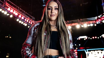 Britt Baker standing in front of a lit wrestling ring photo by Cardoni
