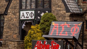 photo of large wooden chair painted with red Greek letters in front of frat house, by Nick Sloff '92 A&A