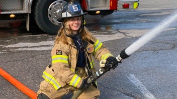 photo of Kollat in firefighter gear wielding a fire hose, courtesy