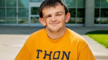 Tucker Haas wearing a yellow THON shirt and standing outside the Bryce Jordan Center by Cardoni