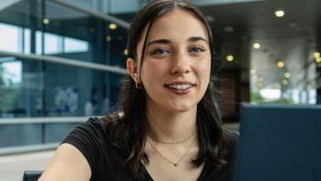 Hailey Onweller sitting at a table with her laptop, photo by Cardoni
