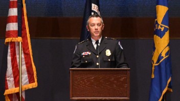 Gallagher standing in military uniform behind a podium with American flag, courtesy