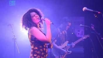 Kat Leverenz singing on a purple-lit stage, courtesy