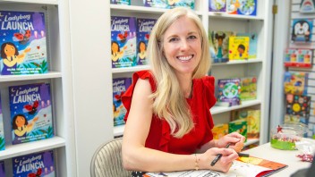 Melissa Trempe seated and signing one of her books, photo by Dayley Photography
