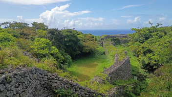 photo of lush green mountains and stone wall in Japan's Ryukyu Islands, courtesy
