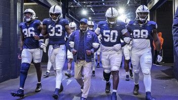 group photo of Smith and players walking onto the field out of a blue tunnel, photo by Mark Selders