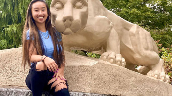 photo of Yu sitting with the Lion Shrine, courtesy