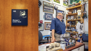 opening spread of Keeper of the Flame featuring a photo of Caldwell's office door and Caldwell standing behind desk inside with PSU football memorabilia on wall and desk by Nick Sloff '92 A&A