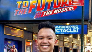 head shot Angud in front of Back to the Future The Musical signage, courtesy