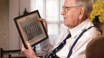 photo of White looking at a framed photo of former Penn State colleagues by Steve Tressler